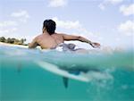 Homme allongé sur une planche de surf dans l'eau