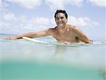 Man sitting on surfboard in water smiling