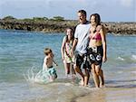 Family of four playing in water outdoors laughing