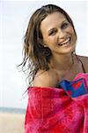 Femme avec une serviette sur la plage souriant