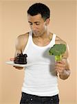 Mann mit Schokoladenkuchen und Brokkoli