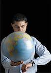 Close-up of a businessman holding a spinning globe and checking the time