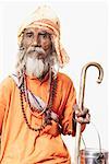 Portrait of a sadhu holding a cane and a utensil