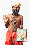 Portrait of a sadhu holding a religious picture