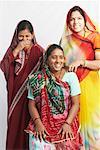 Mid adult woman sitting and two young women standing behind her