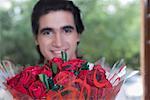 Close-up of a young man hiding behind a bouquet of flowers