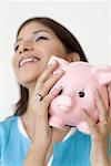 Close-up of a young woman holding a piggy bank and smiling