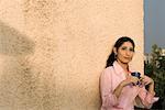 Young woman leaning against a wall and holding a cup of coffee