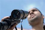 Close-up of a young man holding a pair of binoculars