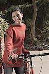 Portrait of a young woman holding a bicycle and smiling