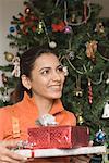 Close-up of a young woman holding Christmas presents and smiling