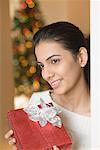 Close-up of a young woman holding a Christmas present and smiling