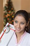 Close-up of a young woman holding a Christmas present and smiling