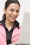 Close-up of a young woman using a laptop and smiling