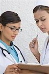 Ärztin und eine Krankenschwester Blick auf ein Klemmbrett