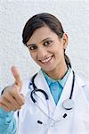 Portrait d'une femme médecin qui signe un pouce en l'air
