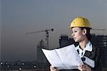 Businesswoman wearing a hardhat and holding a blueprint