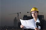 Portrait of a businesswoman wearing a hardhat and holding a blueprint