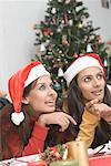 Two young women wearing Santa hats and smiling