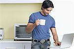 Young man using a laptop and holding a cup of coffee