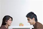 Side profile of a young couple sitting at a table with a present on it