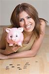 Portrait of a young woman holding a piggy bank