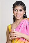 Close-up of a young woman smiling and holding a glass of drink