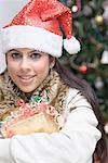 Portrait d'une jeune femme tenant un cadeau et souriant