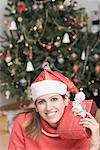 Portrait d'une jeune femme souriante et tenant un cadeau de Noël