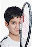 Portrait of a boy holding a tennis racket in front of his face