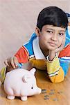 Portrait of a boy putting a coin in a piggy bank