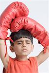 Portrait of a boy wearing boxing gloves and looking sad