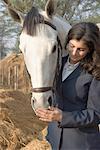 Teenage girl standing with a horse