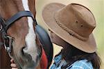 Side profile of a teenage girl touching a horse