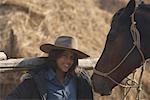 Portrait of a young woman with a horse and smiling at the stable