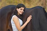 Portrait d'une jeune adolescente debout avec un cheval et souriant