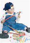 Boy sitting and looking at a paintbrush