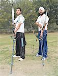 Side profile of two young men holding bows and arrows