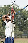 Low angle view of a young man aiming with a bow and arrow