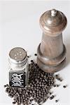 Close-up of a peppermill and a pepper shaker with peppercorns