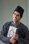Portrait of a young man holding the Koran and smiling