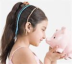 Side profile of a girl holding a piggy bank