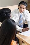 Real estate agent discussing a document with a young couple