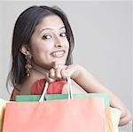 Portrait d'une jeune femme transportant des sacs à provisions et souriant