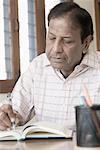 Close-up of a mature man writing in a diary