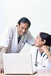 Female doctor with a male doctor in front of a laptop