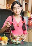 Portrait d'une jeune fille salade de mélange avec une cuillère en bois