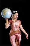 Portrait of a young woman performing Bharatnatyam and holding a globe