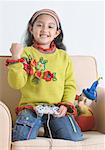 Portrait d'une jeune fille à genoux sur un fauteuil et jeu vidéo
