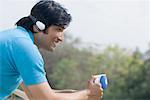 Profil de côté d'un jeune homme tenant une tasse de café et d'écouter de la musique